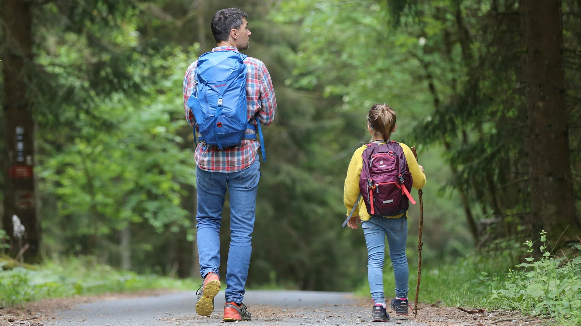 man in blue jacket and blue denim jeans walking on dirt road during daytime